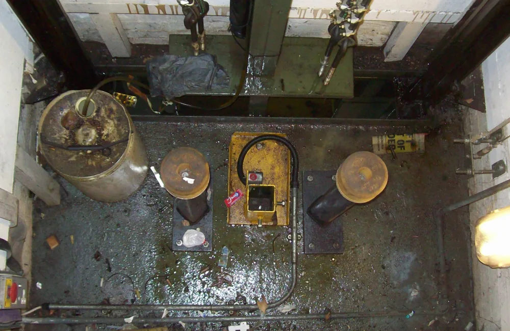 Looking down into a lift shaft with the roof of the lift covered in grease, dirt and rubbish.