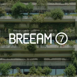 A multi‑story building façade with horizontal concrete ledges covered in dense green plants and shrubs, with large glass windows behind them. The centre text reads ‘BREEAM 7.