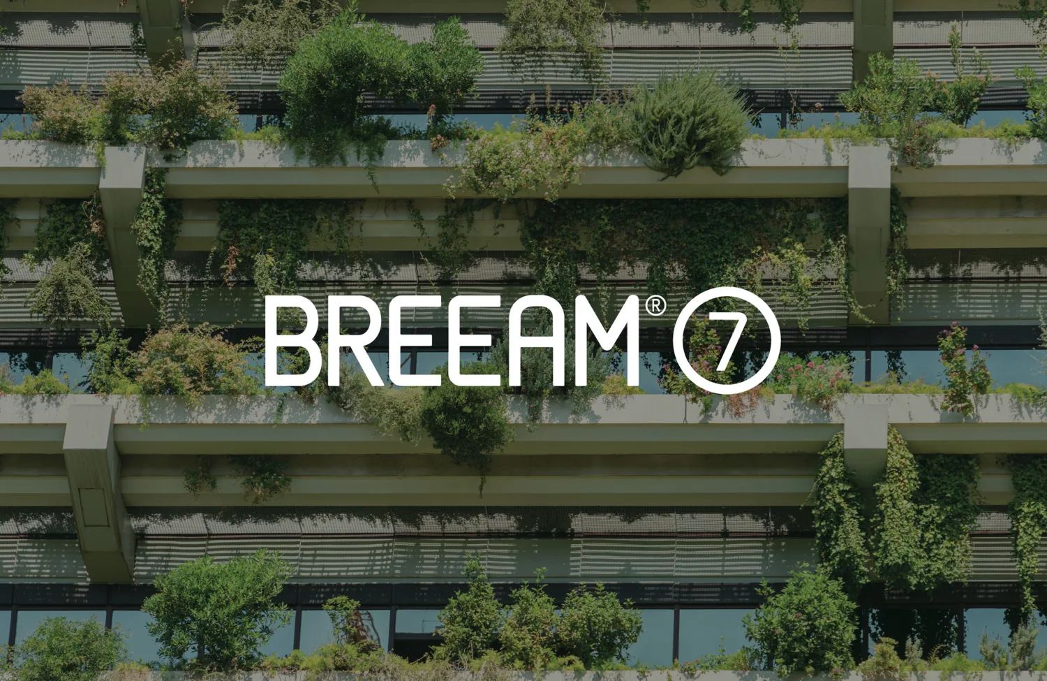 A multi‑story building façade with horizontal concrete ledges covered in dense green plants and shrubs, with large glass windows behind them. The centre text reads ‘BREEAM 7.