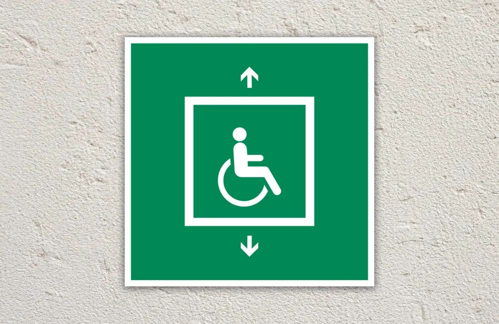 Green evacuation for people unable to use stairs sign sign on a cream painted wall.