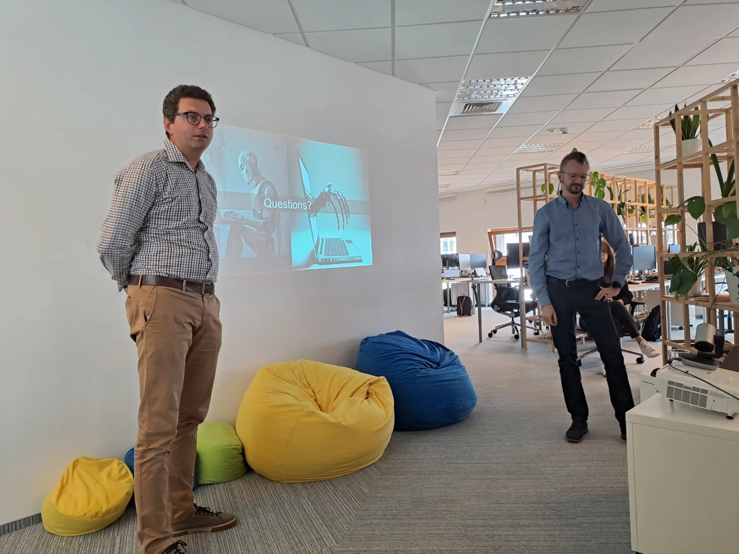 Speaker standing in office presenting with projection of presentation on wall