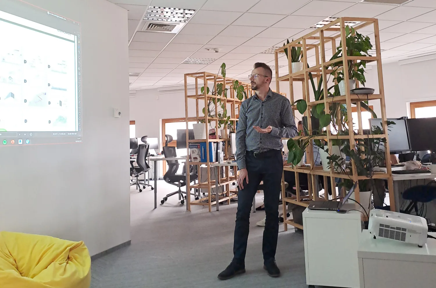 Speaker standing in office presenting with projection of presentation on wall