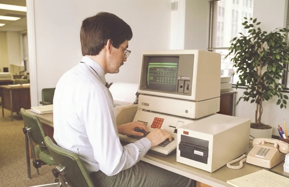 80s themed apple computer with man sitting at the desk