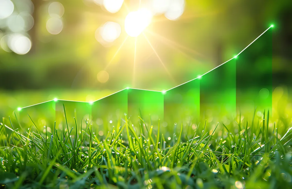Close-up of green grass with sunlight in the background and a glowing green upward trend line overlay
