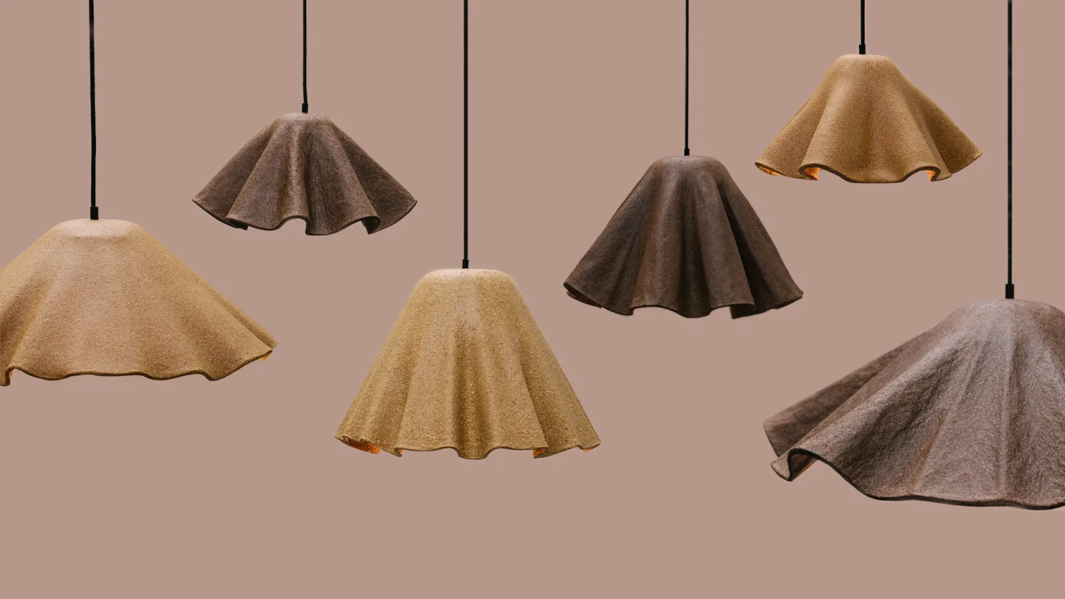 Multiple Obscure lampshades of varying colours hanging up against a plain background