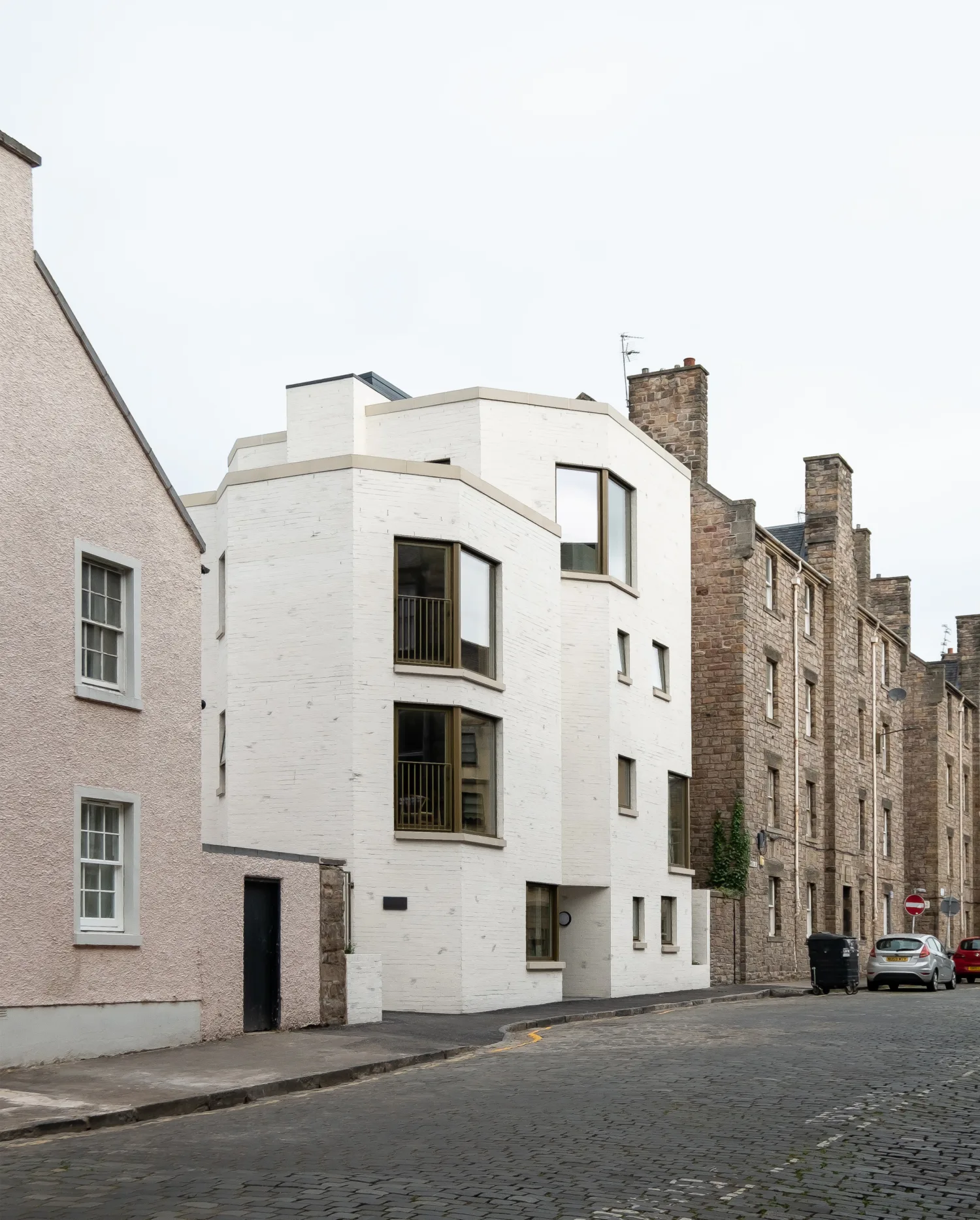 White front building on a residential street against a grey sky