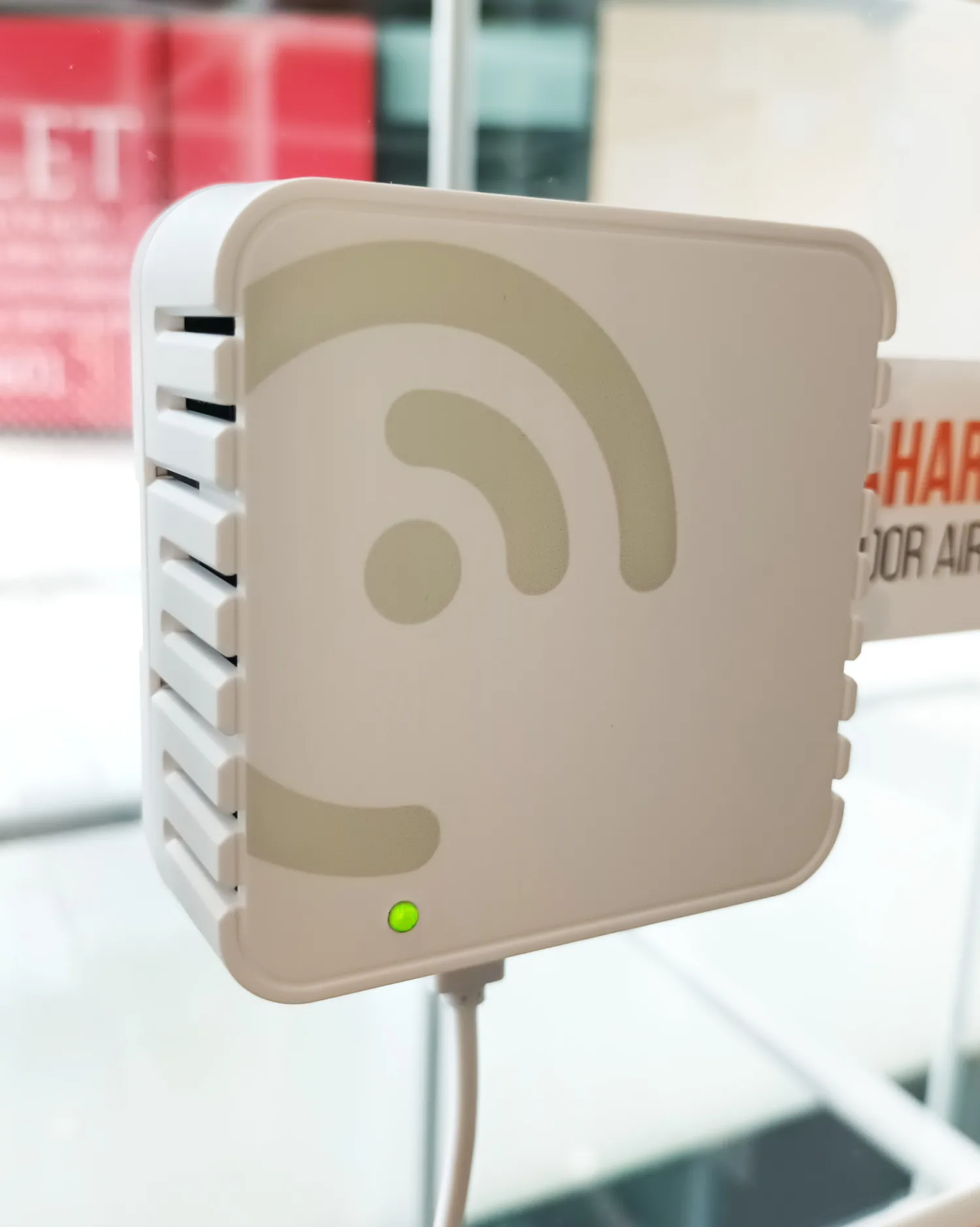 Square white plastic console mounted onto a transparent surface, with a light indicator showing green