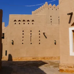 a {     text-decoration: none;     color: #464feb; } tr th, tr td {     border: 1px solid #e6e6e6; } tr th {     background-color: #f5f5f5; }   Sunlit alley between sand-colored buildings with geometric cut‑out patterns, wooden window frames, wall-mounted lights, and a paved stone walkway under a clear blue sky.