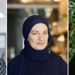 Three side‑by‑side portrait photos showing individuals indoors and outdoors. From left to right: a person with shoulder‑length hair in a patterned top inside an office setting; a person wearing a dark head covering and dark top indoors; and a person with closely cropped hair wearing a dark sweater, standing in front of green plants.