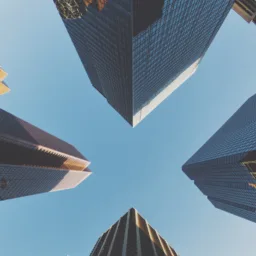 Looking up at tall glass skyscrapers against a blue sky