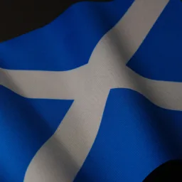 Close-up of the Scottish flag showing a white diagonal cross on deep blue fabric, with visible woven texture and soft folds creating light and shadow across the cloth.