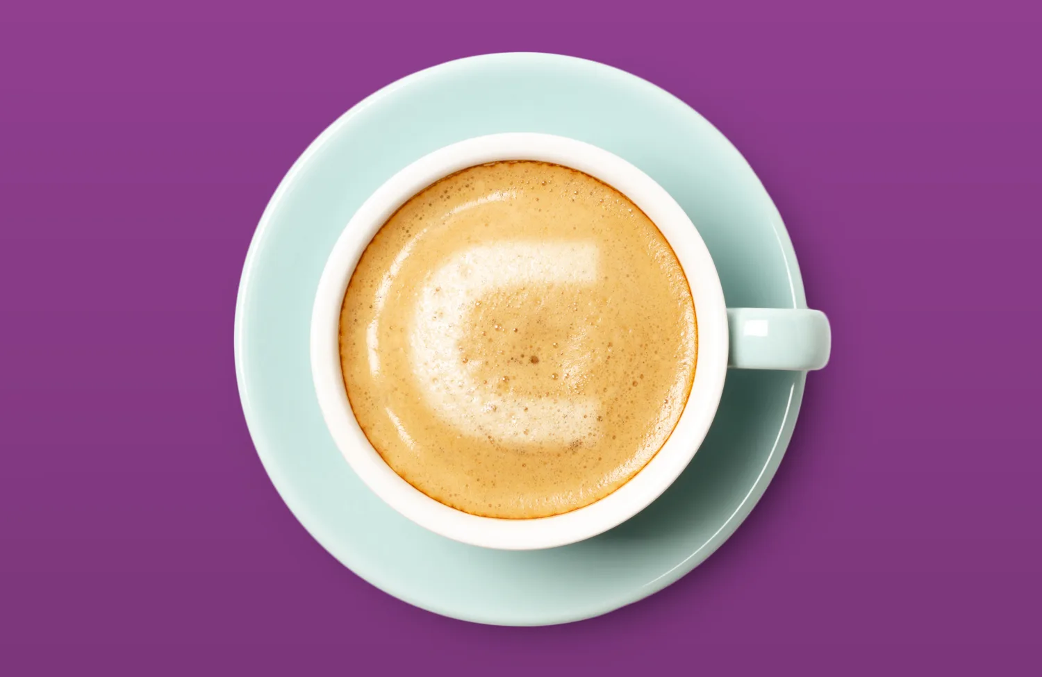 A top view of a cup of frothy coffee in a light blue saucer against a solid purple background. The foam on the coffee surface forms a stylised curved shape resembling the letter C.