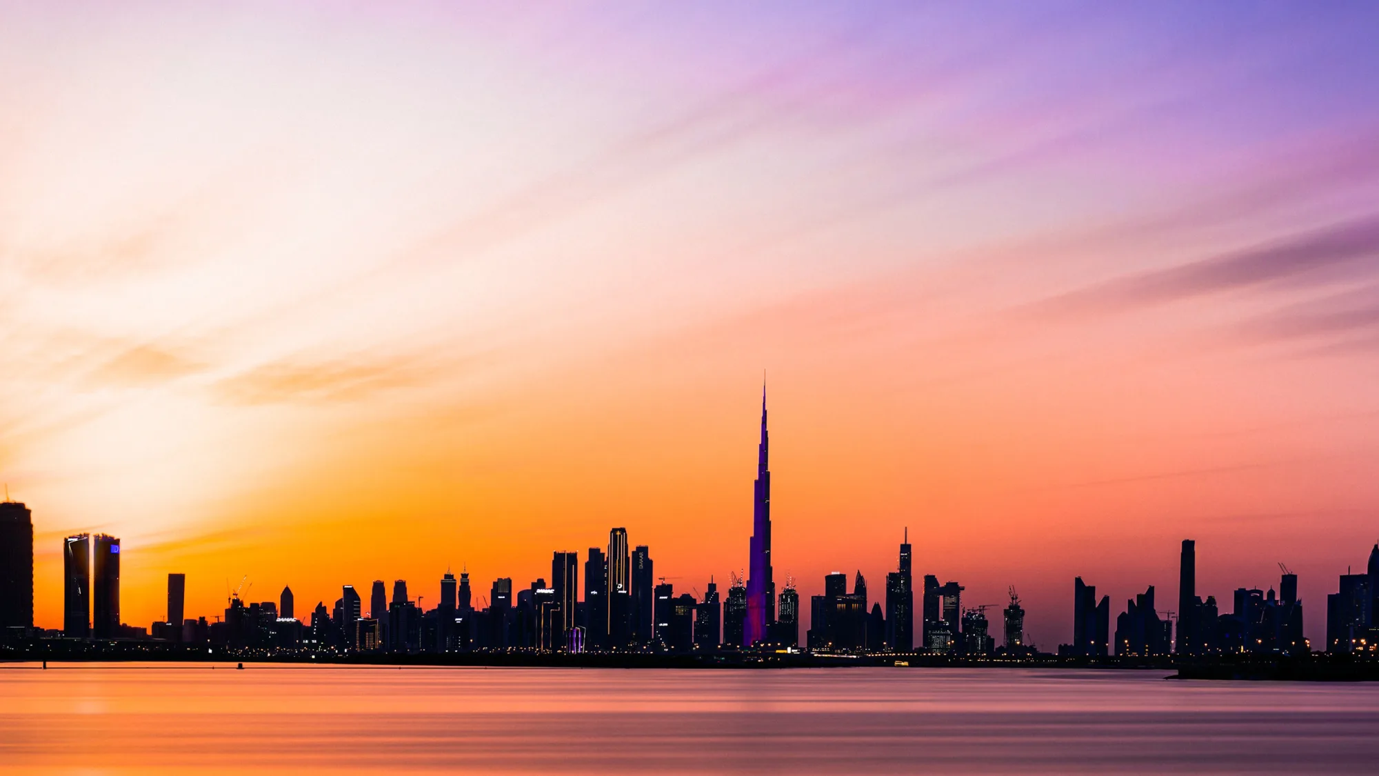 Silhouette Of Dubai buildings against the ocean and a sunsetting sky