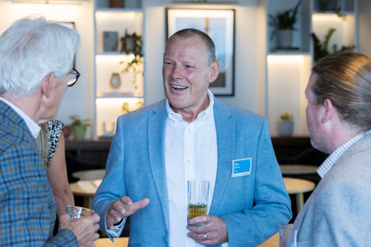 Three people engaged in conversation with lit shelving in the background