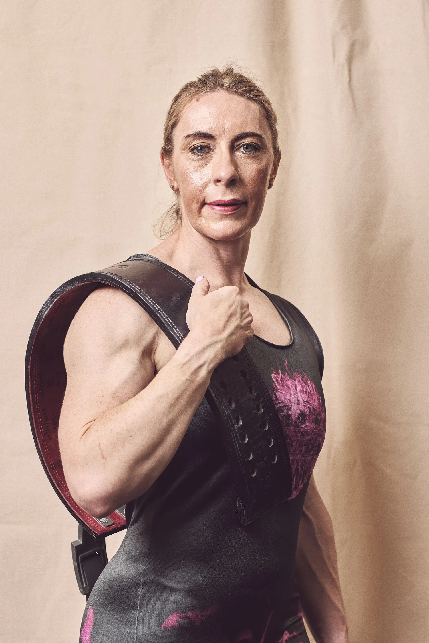 Carole in with her weightlifting belt on her shoulder looking to camera