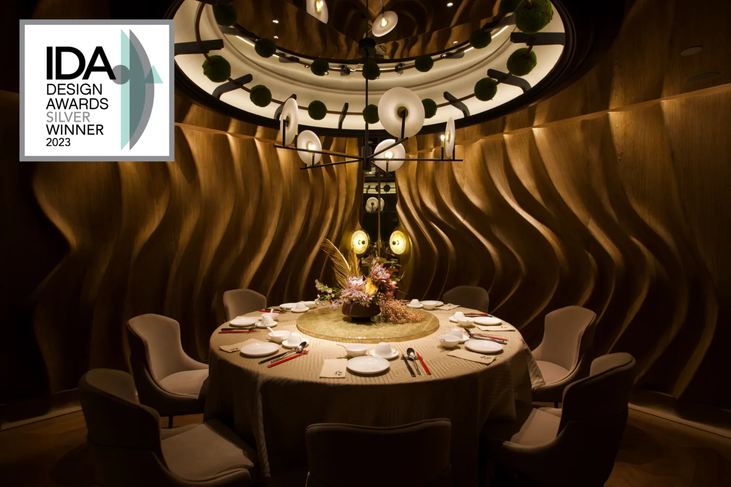 Dining room in Azure with modern lighting, chair and tables complemented by a swirly walled texture enhanced by lights.