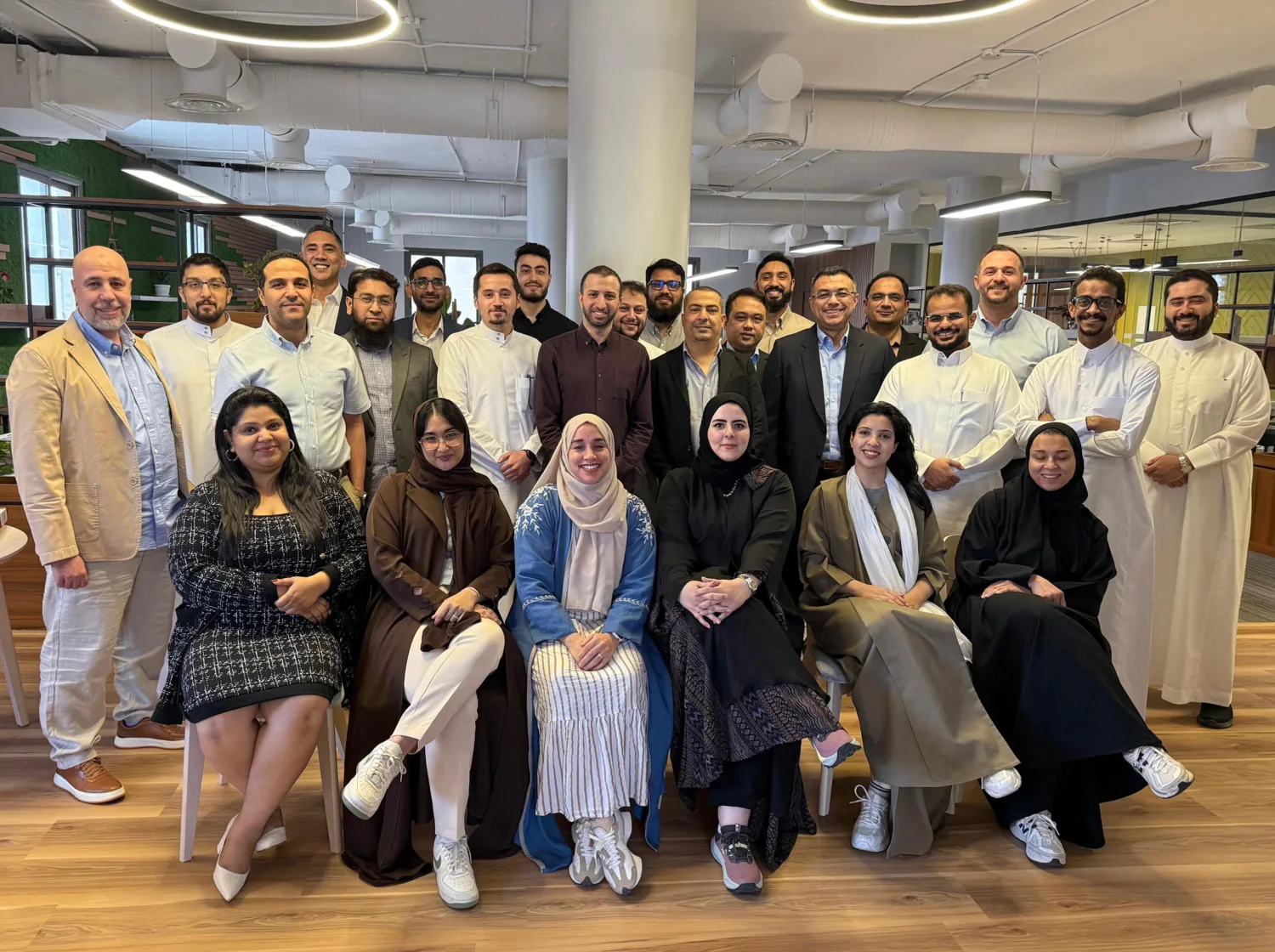 The office team sat and standing in a tiered formation under the circular office lights.