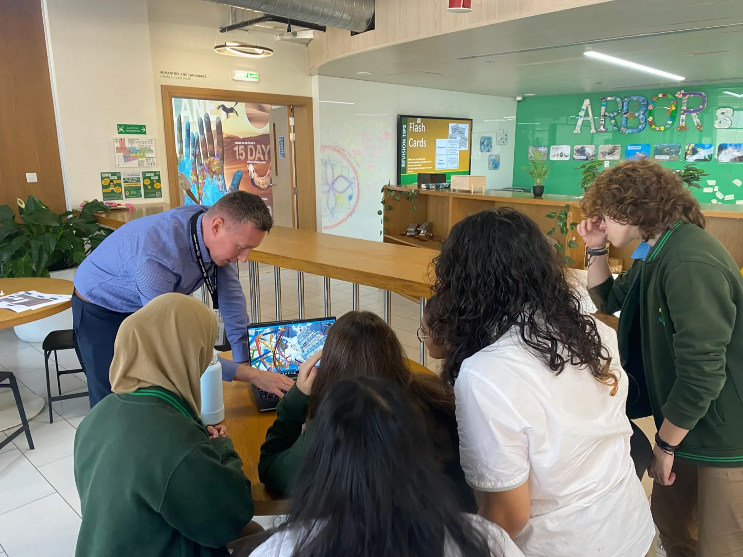 Engineer leaning over a laptop and showing a BIM demo to four students in a classroom