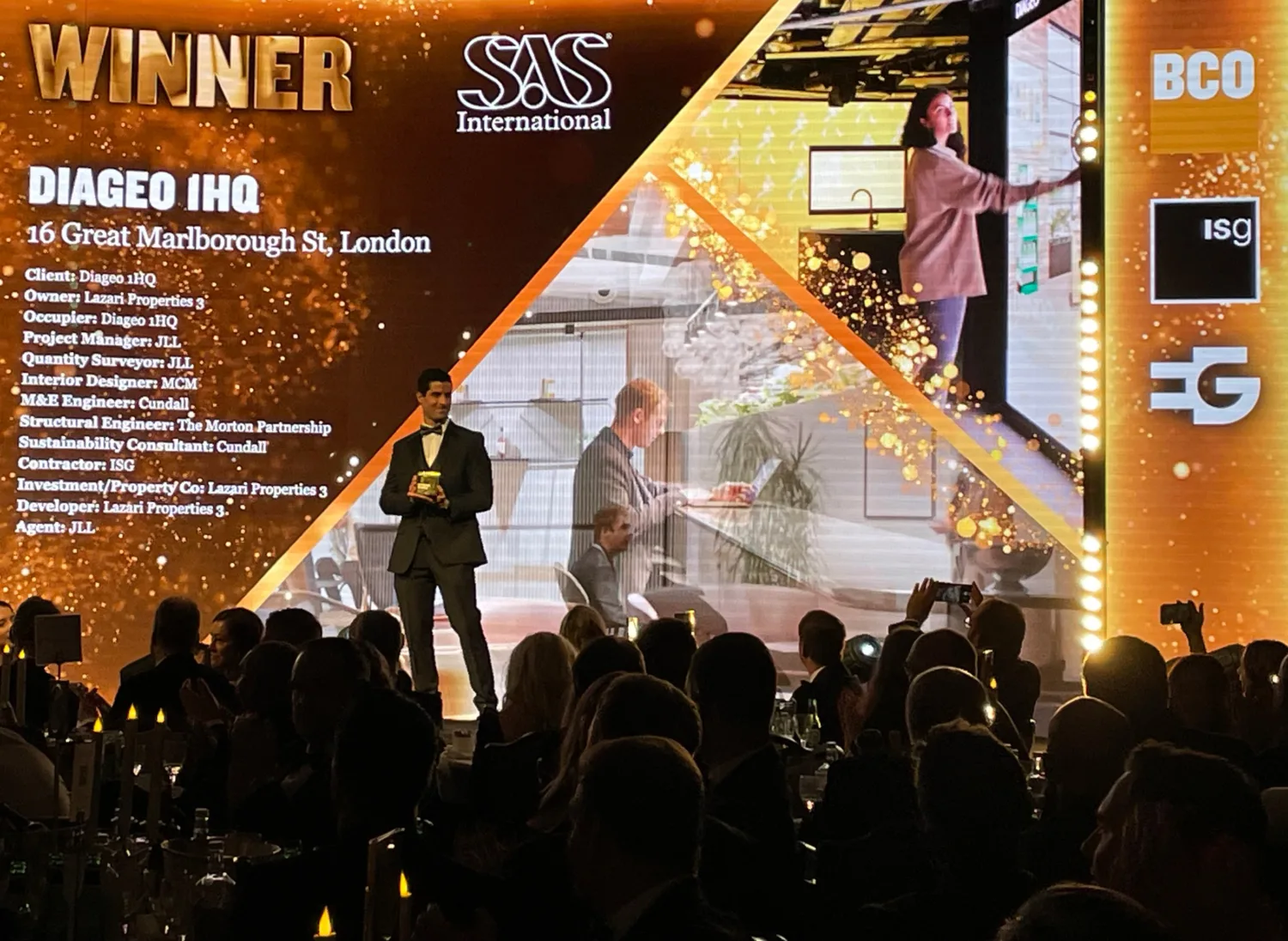 Awards presenter on stage in front of the WINNER Diageo 1 HQ screen