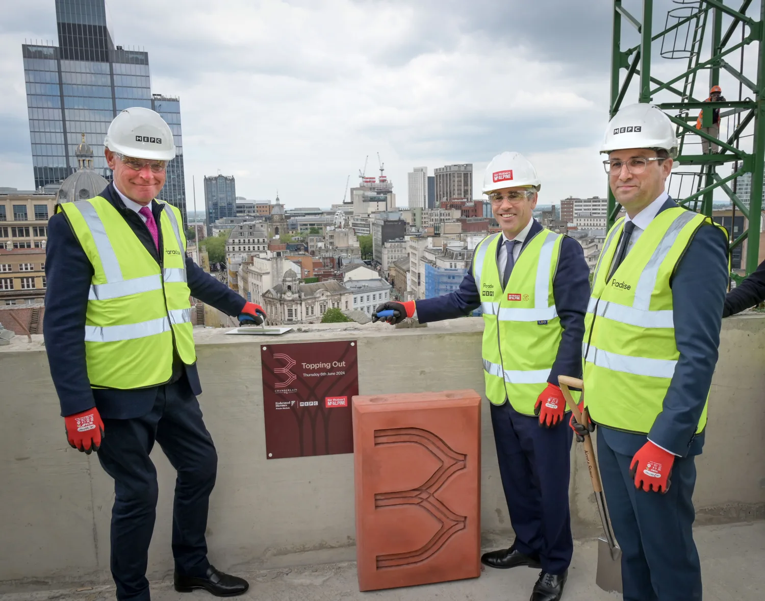 'Topping out' plaque with three people in suits and PPE