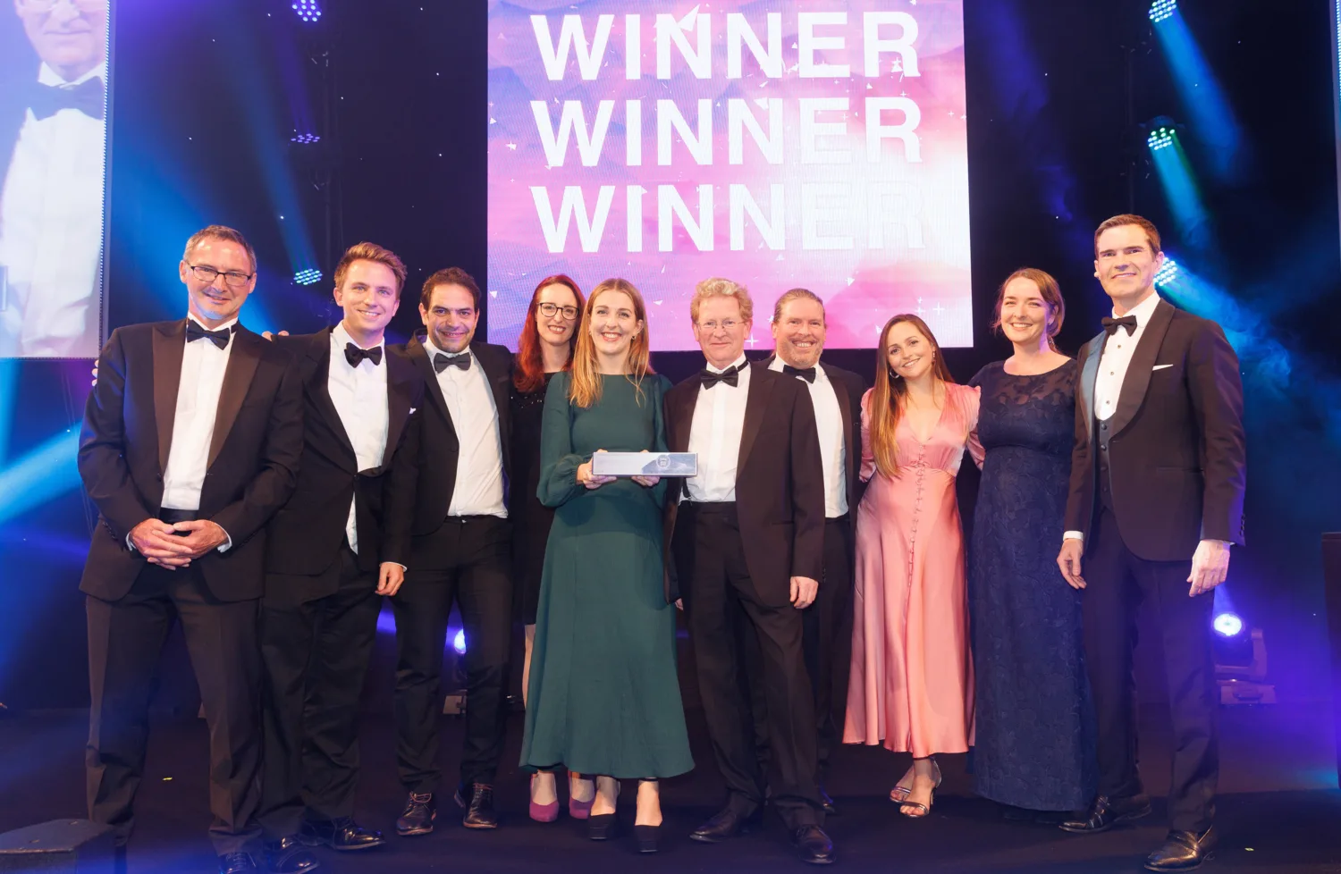 Cundall Engineering team in formal dress on stage with Jimmy Carr underneath a Winner sign