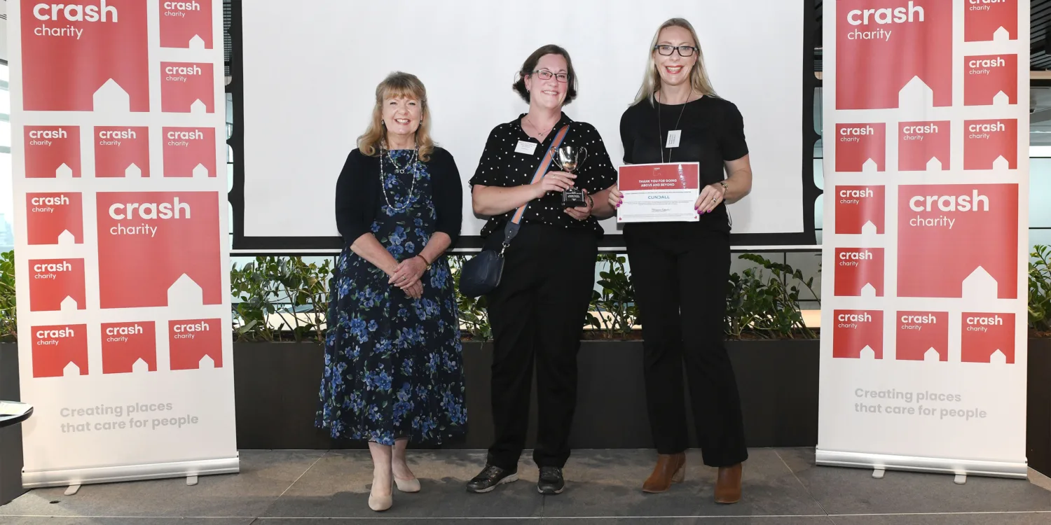 Natasha and Carol on stage recieving the crash award holding up the certificate and the trophy