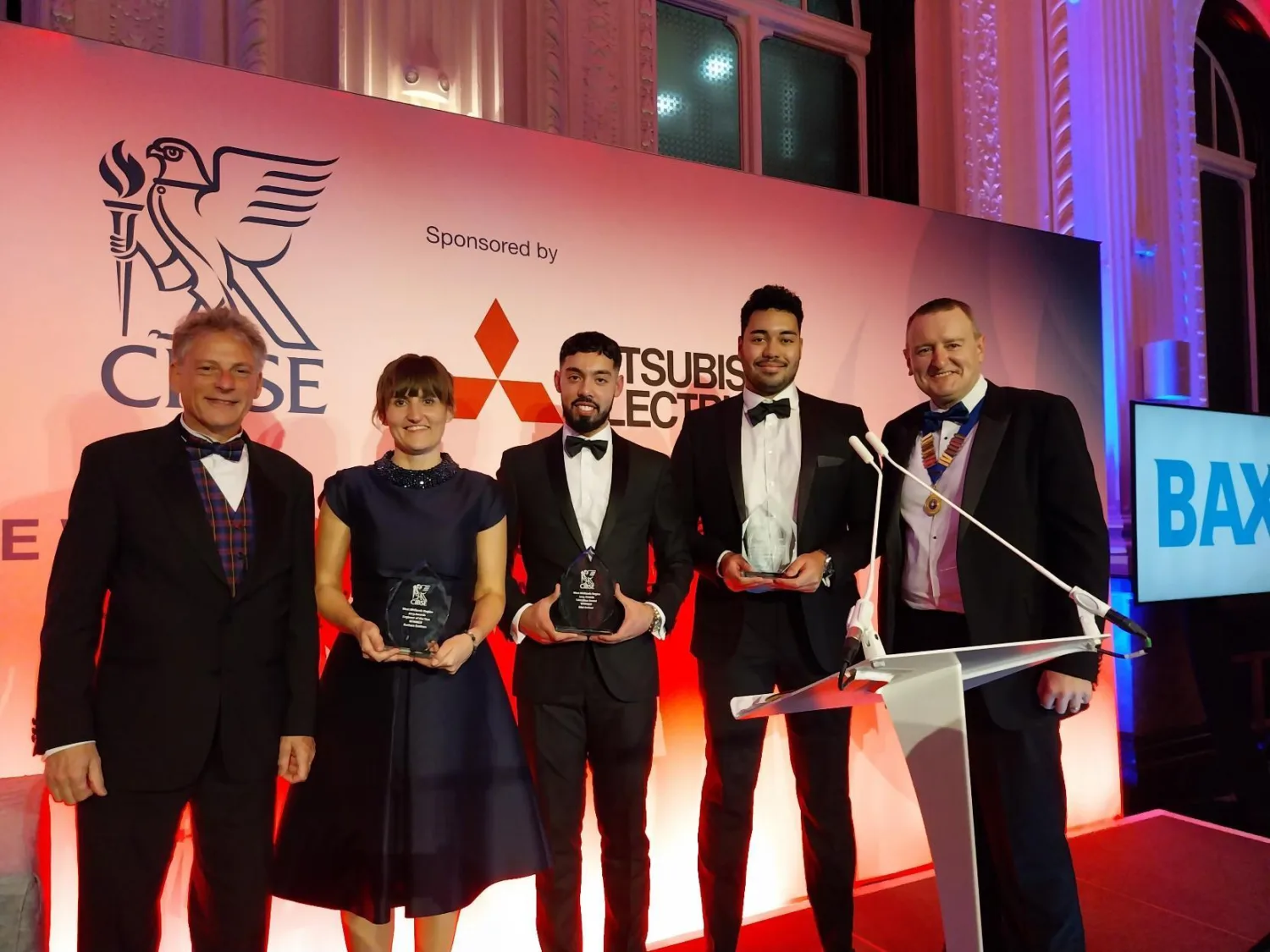 A group of five people standing in a line, the three in the middle are holding CIBSE West Midlands awards