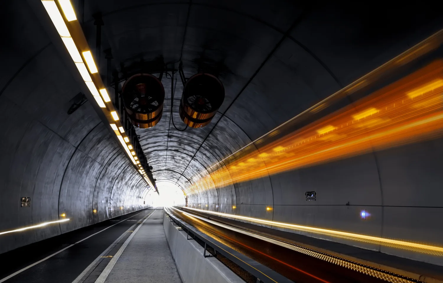 Dark road tunnel with ventilation and bright orange light trails