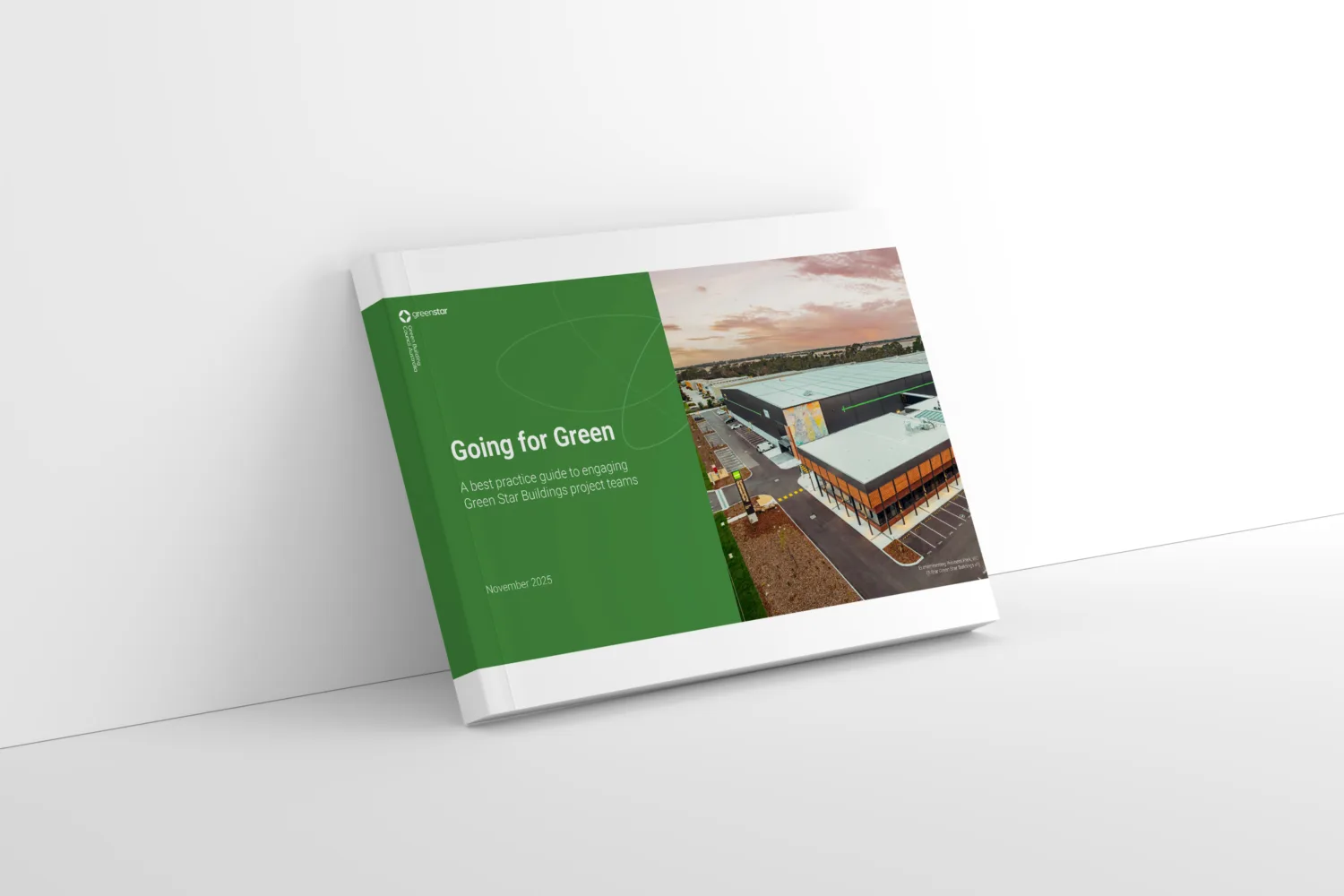 Landscape-oriented book with a white spine and cover featuring a green section on the left and an aerial photo of a modern building complex on the right. The green section includes white text reading “Going for Green” and smaller text beneath it. The book is placed on a white surface against a white wall.