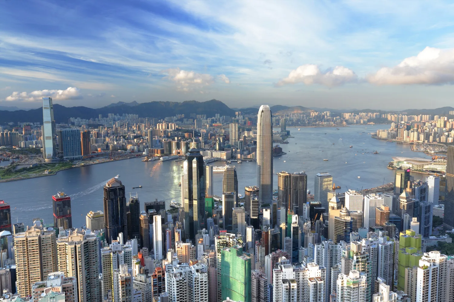 Hong Kong skyline in which a river and cloudy blue sky are both visible