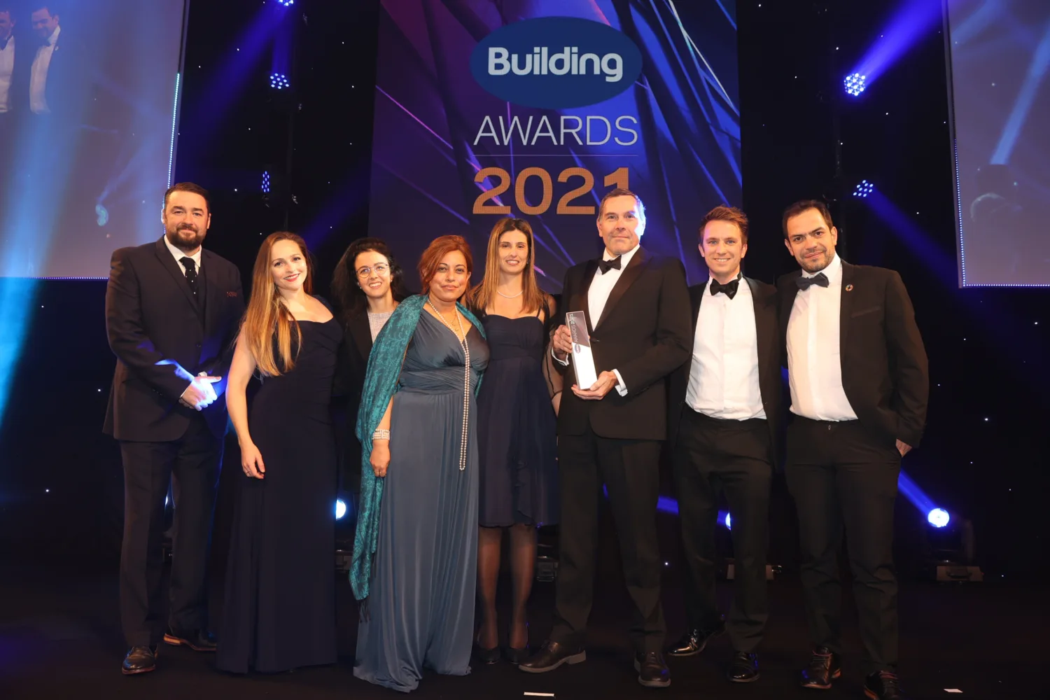 The team looking at the camera, holding the award with the Building Awards 2021 logo on the wall behind