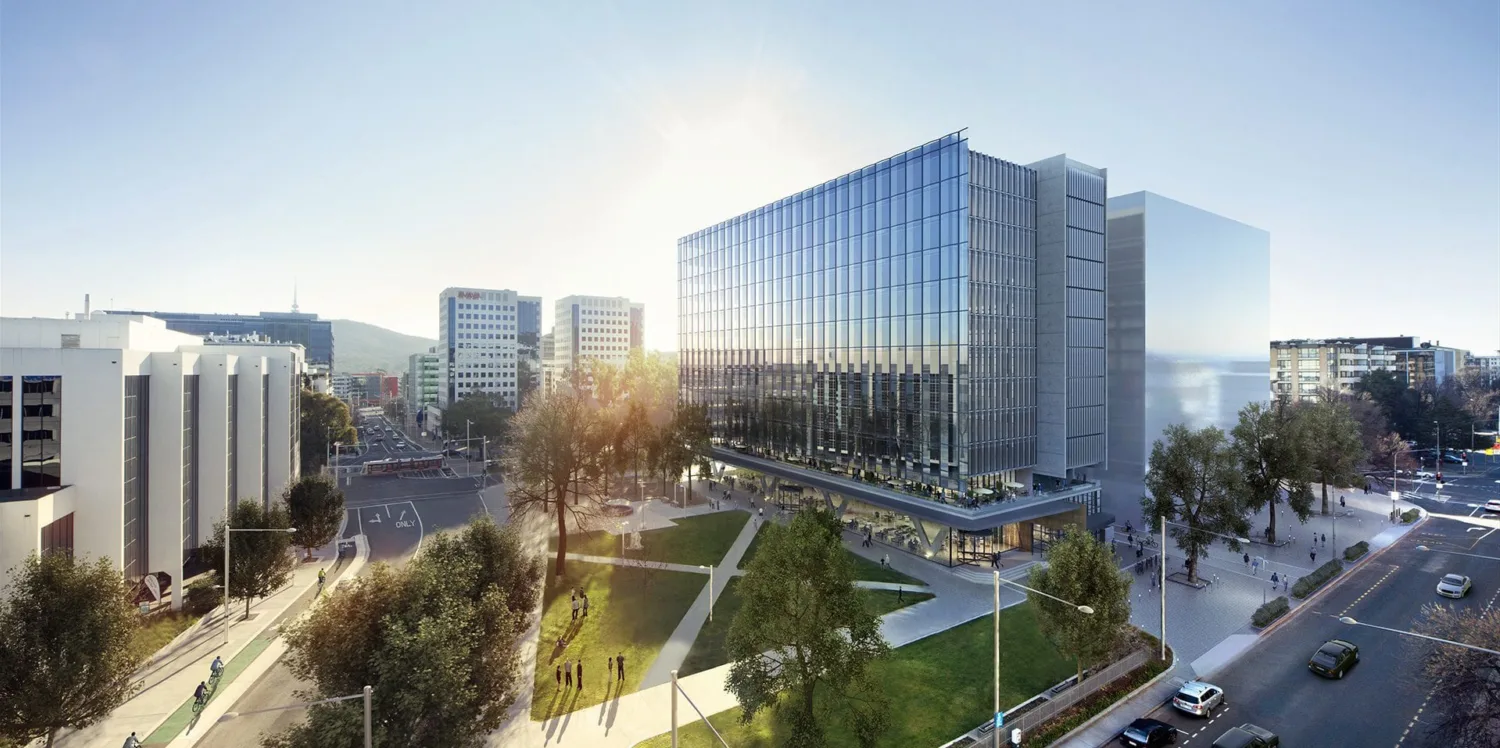 Large glass building overlooking a grassy courtyard against a blue sunny sky