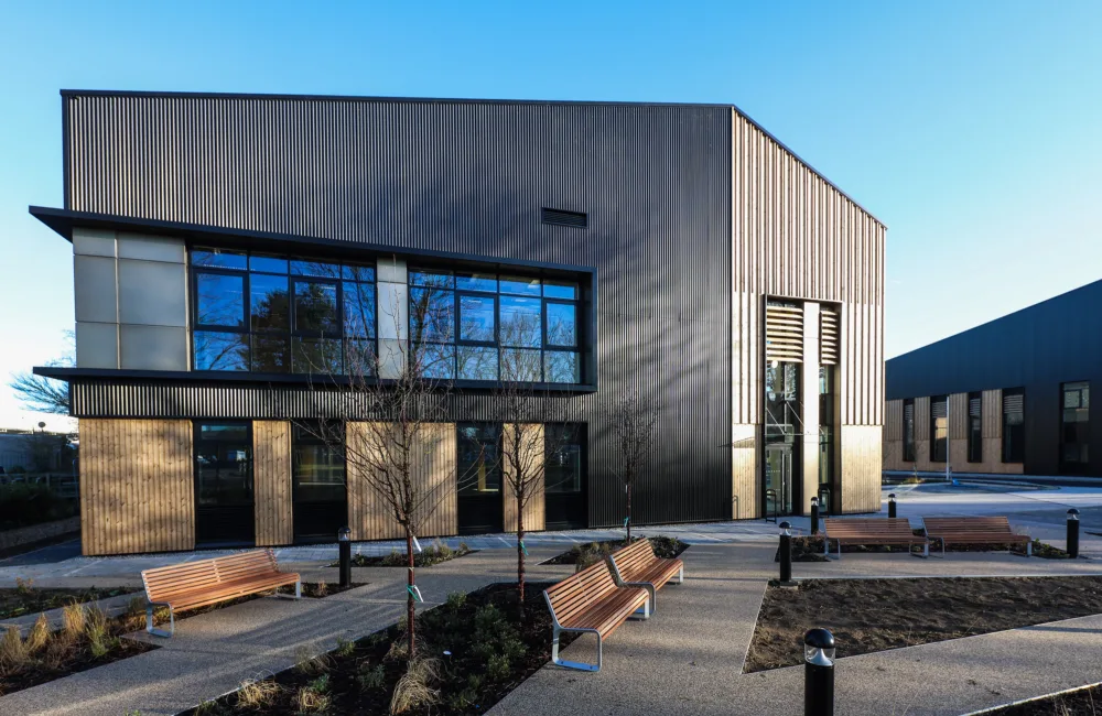 View of frant facade of building showing wooden cladding and glazing, a bright day with blue sky
