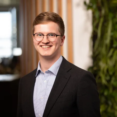 Tim in a blue shirt and suit jacket in front of a living wall