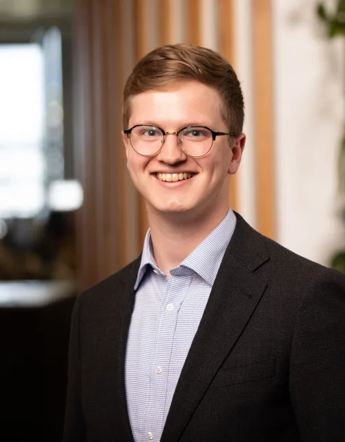 Tim in a blue shirt and suit jacket in front of a living wall