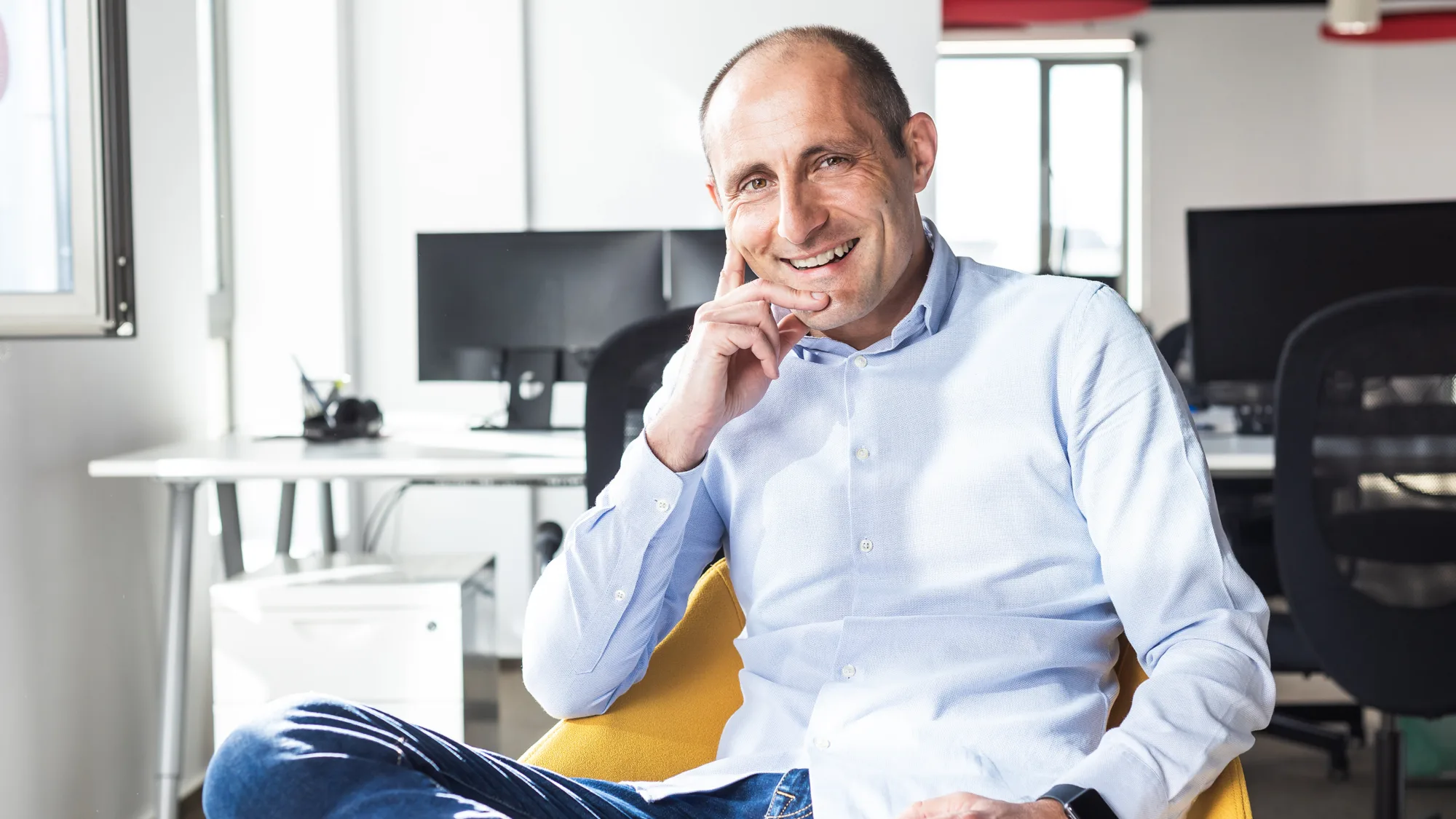 Horia sat in a yellow chair with his legs crossed wearing jeans and a pale blue shirt