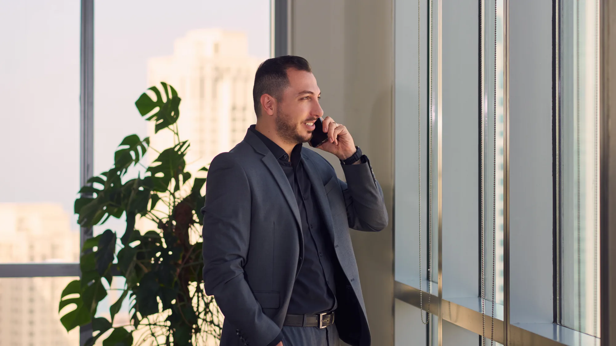 Mario Saab is having a conversation using his mobile phone beside the windows.