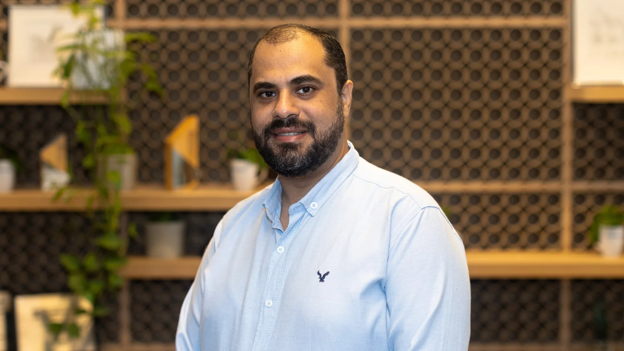 Mina Zachary in a light blue Oxford shirt against a wood textured office background