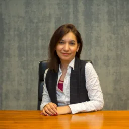 Rabia sat at a wooden table in a white shirt and waistcoat