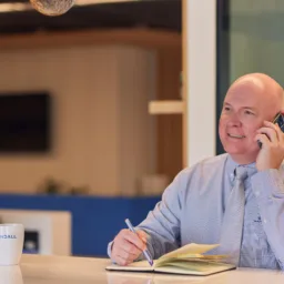 Richard Stratton smiling while talking on a mobile phone and taking notes