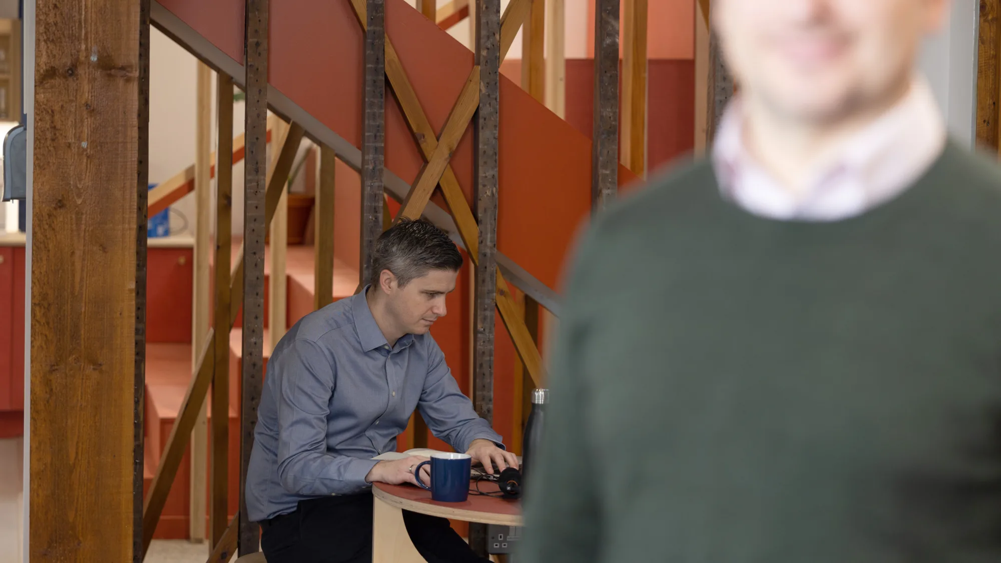 Derry Kearney at hot desk table in background