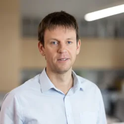 Tom Kennedy smiling in an office wearing a blue shirt