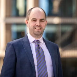 Duncan wearing a purple shirt and tie and suit jacket