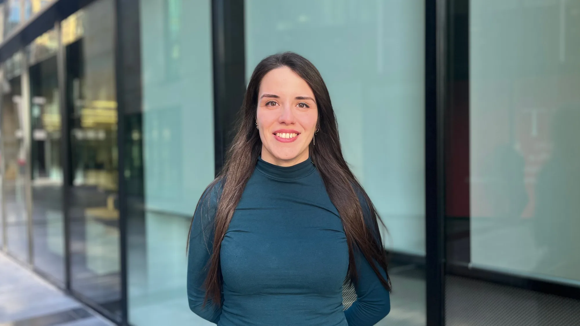 Head and shoulders image of Irene Vogiatizi wearing a blue long sleeved top standing outside with sunset lighting
