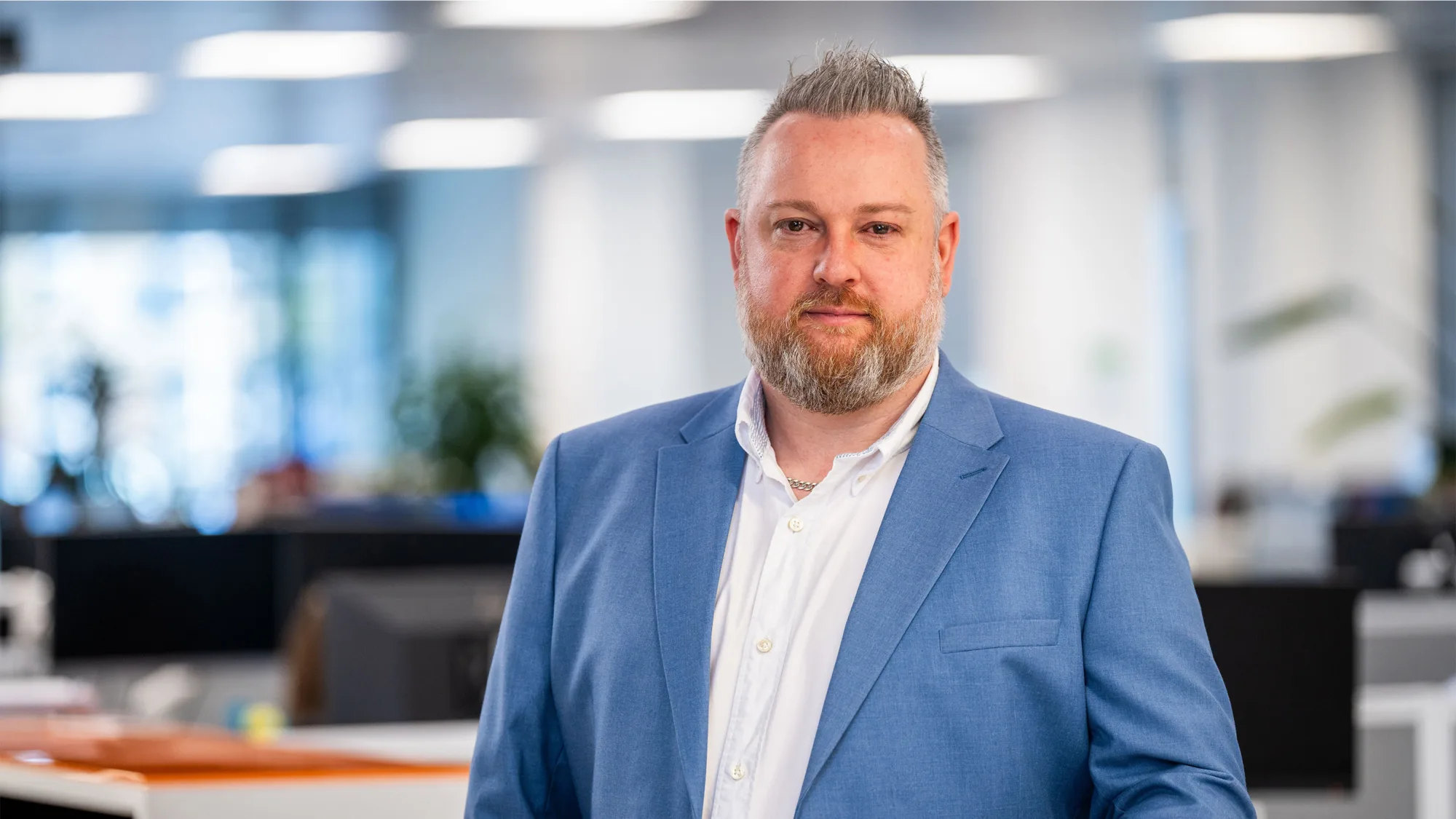 Keith Richardson standing in the Edinburgh office in a white shirt and blue blazer