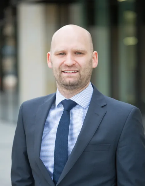 Robert in a suit and navy tie stood outside of the Edinburgh office