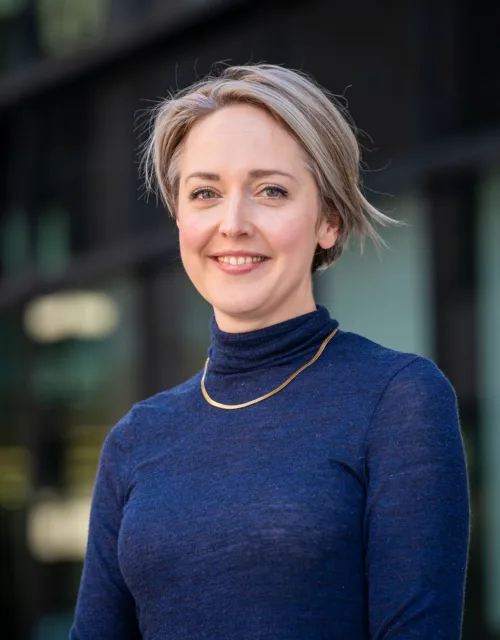 Sophie Simpson smiling looking towards the camera wearing a dark blue top