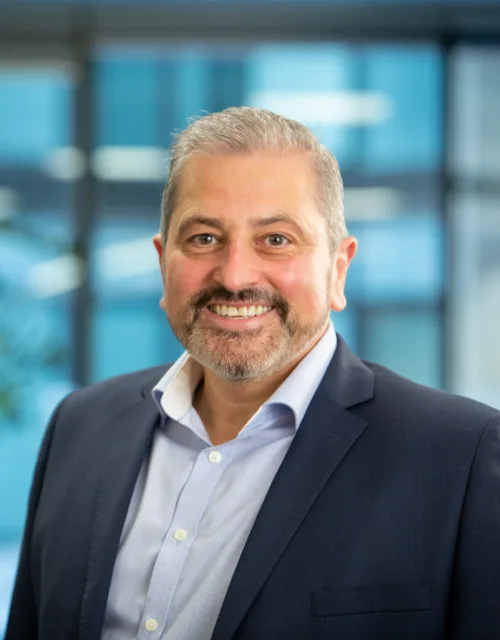 Tony Centola in dark suit with planting and glass office area background blurred