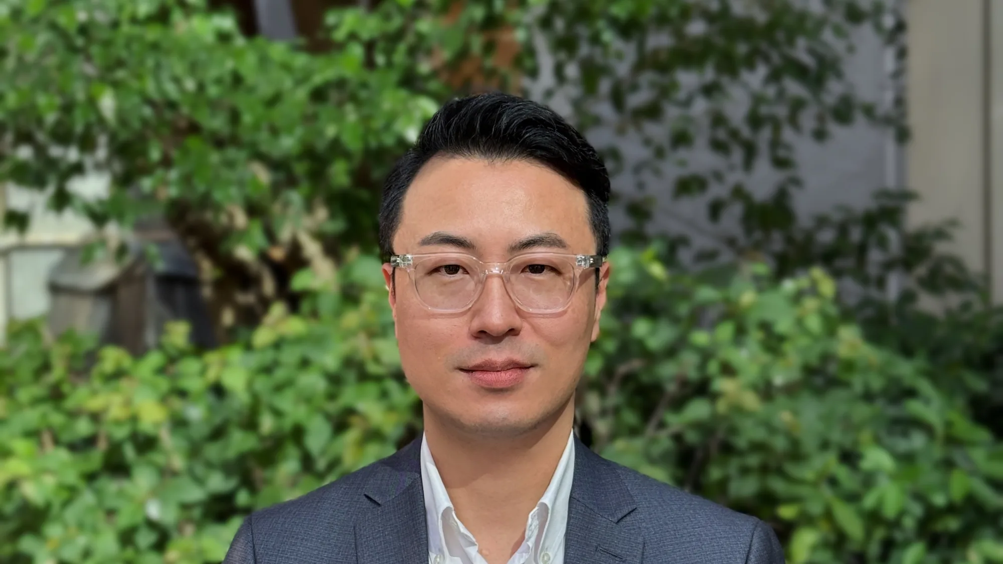 Byeonghee in a shirt and suit jacket looking to camera outside