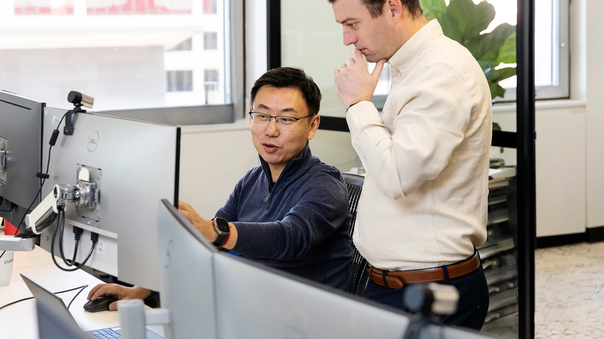 Dong Chen sitting talking through a project and pointing to screen